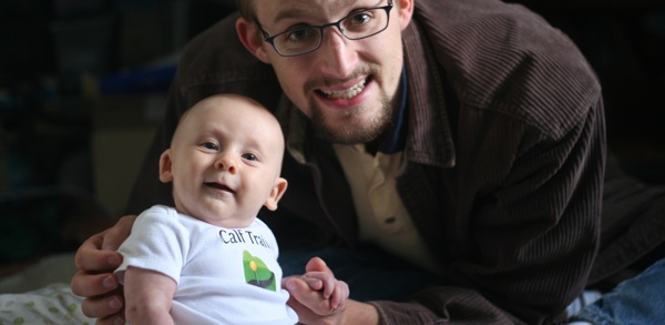 Software developer holding smiling son, who is proudly wearing a company logo