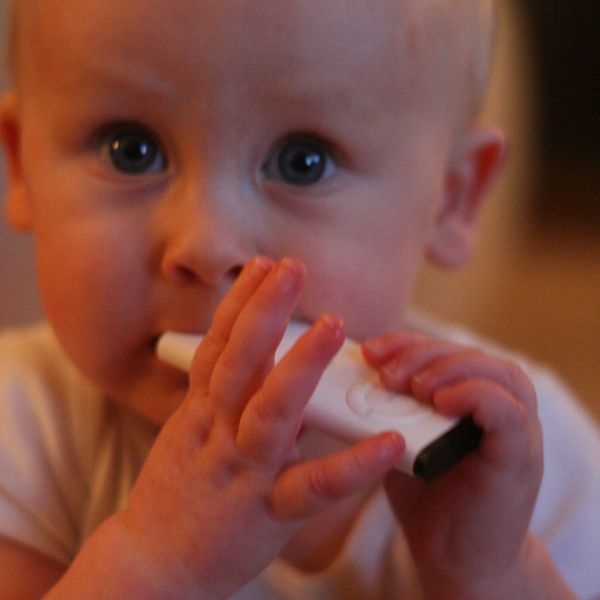 Toddler chewing on white plastic remote